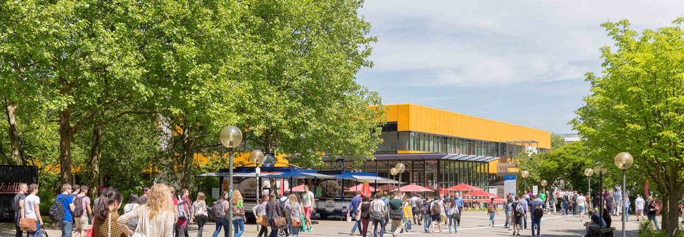 Campusleben mit Studierenden und Mensa im Hintergrund